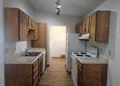 Thumbnail 4 of 16 - A kitchen with wooden cabinets and a white stove top oven.