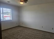 Thumbnail 7 of 16 - A room with a ceiling fan and carpeted floor.