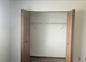 Thumbnail 9 of 16 - A white wall with a wooden closet door open.
