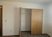 Thumbnail 8 of 16 - A room with a wooden door and a carpeted floor.