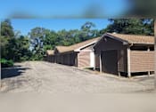Thumbnail 4 of 4 - A row of garages are lined up on a gravel lot.