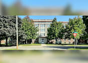 Thumbnail 1 of 4 - A street view with a building in the background and a yield sign in the foreground.