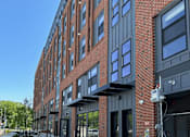 Thumbnail 1 of 29 - a red brick apartment building with gray and black facade