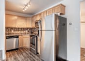 Thumbnail 5 of 16 - A kitchen with a stainless steel refrigerator and wooden cabinets.
