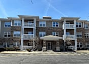 Thumbnail 1 of 37 - A large apartment building with a parking lot in front.