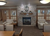 Thumbnail 20 of 37 - a living room with a stone fireplace and a table and chairs