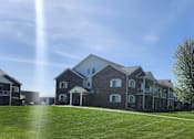 Thumbnail 18 of 21 - A large house with a green lawn in front.