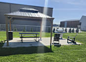 Thumbnail 16 of 21 - A picnic area with a bench and a table is set up in a grassy area.