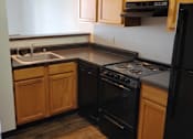 Thumbnail 11 of 21 - A black stove and oven in a kitchen with wooden cabinets.