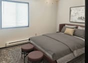 Thumbnail 3 of 7 - A bedroom with a bed, two stools, and a window.