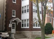 Thumbnail 1 of 9 - A tree with orange leaves stands in front of a red brick building.