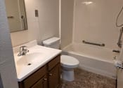 Thumbnail 6 of 14 - A bathroom with a toilet, sink, and bathtub.