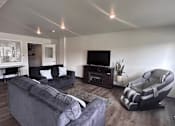 Thumbnail 11 of 19 - A living room with a grey couch and a black chair.