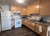 Thumbnail 2 of 19 - A kitchen with wooden cabinets and a white refrigerator.