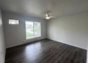 Thumbnail 4 of 19 - A room with a ceiling fan and a window overlooking a green area.