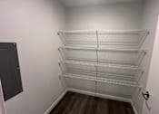 Thumbnail 7 of 19 - A walk in closet with shelves and a door.