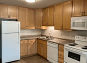 Thumbnail 5 of 15 - A kitchen with white appliances and wooden cabinets.