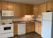 Thumbnail 3 of 15 - A kitchen with white appliances and wooden cabinets.