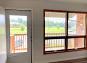 Thumbnail 7 of 15 - A room with a view of a deck and a house through the window.