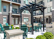 Thumbnail 18 of 54 - A patio with green chairs and a table is surrounded by apartment buildings.