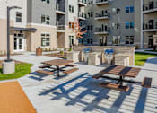 Thumbnail 37 of 80 - Picnic tables are set up on a patio in front of apartment buildings.
