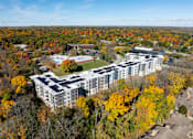 Thumbnail 38 of 80 - A large white building with a green roof surrounded by trees with orange and yellow leaves.