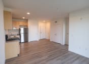 Thumbnail 8 of 39 - an empty living room and kitchen with wood floors and white walls
