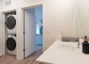 Thumbnail 12 of 39 - a white bathroom with a washer and dryer in it and a white sink