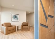 Thumbnail 14 of 39 - a living room with two brown chairs and a hallway with a blue accent wall