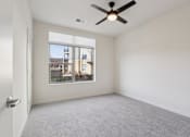 Thumbnail 16 of 80 - A room with a ceiling fan and a large window overlooking a cityscape.