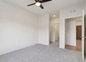 Thumbnail 17 of 80 - A room with a ceiling fan and carpeted floor.
