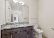 Thumbnail 21 of 80 - A bathroom with a marble counter top and white toilet.