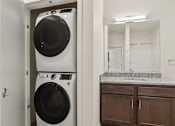 Thumbnail 22 of 80 - A white washer and dryer in a small laundry room.