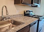 Thumbnail 7 of 80 - A kitchen with a granite countertop and stainless steel appliances.