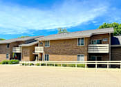 Thumbnail 2 of 8 - A large brick building with a white fence in front.