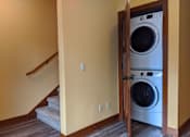 Thumbnail 19 of 29 - A washer and dryer are in a small wooden cabinet in a home.