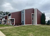 Thumbnail 36 of 36 - A modern house with a red brick exterior and a grey door.