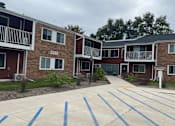 Thumbnail 35 of 36 - A parking lot in front of apartment buildings with blue stripes on the pavement.