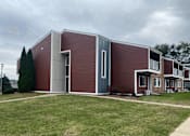 Thumbnail 3 of 36 - A modern building with a red brick exterior and a grey roof.