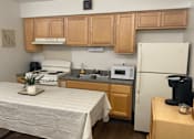 Thumbnail 18 of 36 - A kitchen with a table and a fridge.