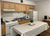 Thumbnail 19 of 36 - A kitchen with a white stove and a white table with a plant on it.