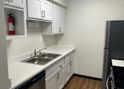 Thumbnail 8 of 36 - A kitchen with white cabinets and a black dishwasher.