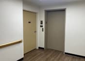 Thumbnail 6 of 36 - A hallway with two doors and a wooden handrail.