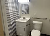 Thumbnail 15 of 36 - A bathroom with a toilet, sink, and striped shower curtain.