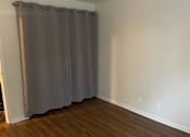 Thumbnail 14 of 36 - A room with a grey curtain and wooden floor.
