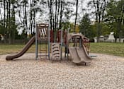 Thumbnail 27 of 36 - A playground with a red and grey slide and a brown slide.