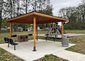 Thumbnail 26 of 36 - A wooden pavilion with a playground in the background.
