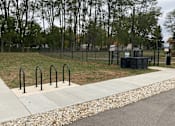 Thumbnail 32 of 36 - A park with a fence, trees, and a trash can.