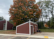 Thumbnail 24 of 36 - A red building with a white door is situated in a parking lot.