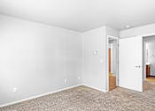 Thumbnail 13 of 25 - A room with white walls and a carpeted floor.